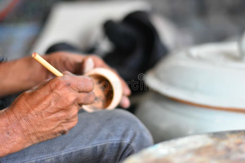 Hands of artist using the tools to drawing in the brown earthenware. Close up and selective focus Hands of artist using the tools to drawing in the brown royalty free stock photography