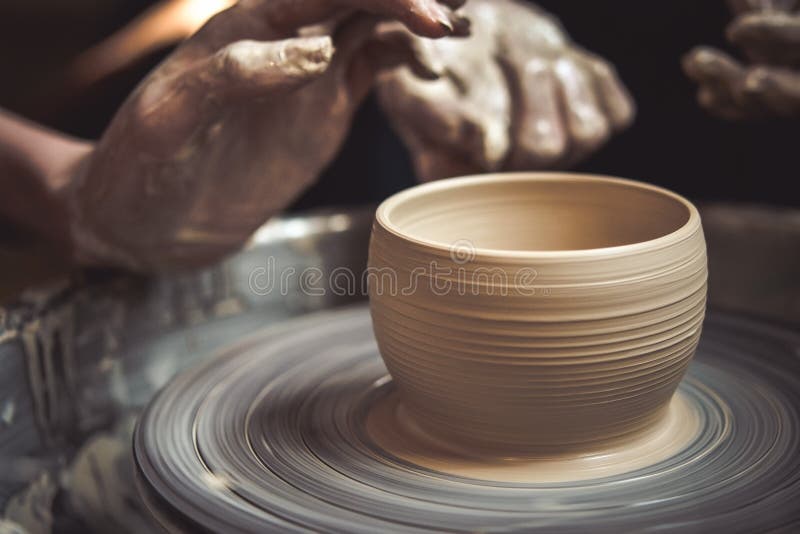 Creating vase of white clay close-up. Master crock. The sculptor in the workshop makes a jug out of earthenware closeup. Twisted potter`s wheel. Man hands stock images