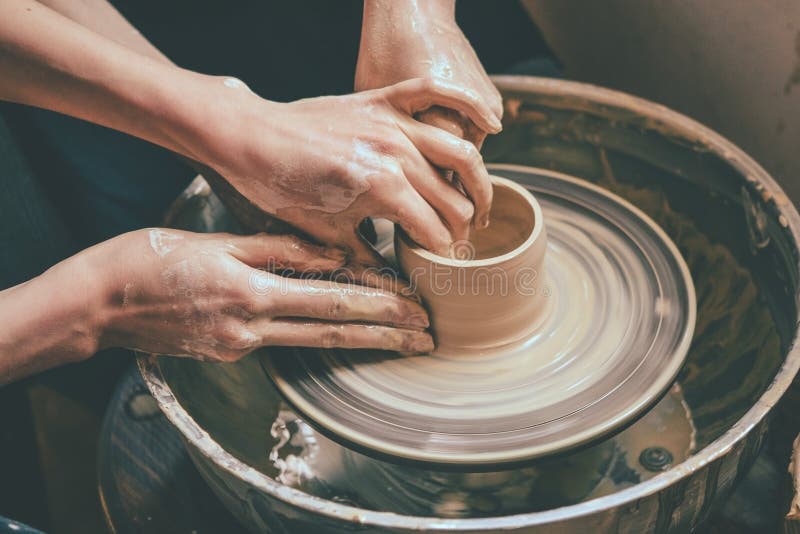 Creating vase of white clay close-up. Master crock. The sculptor in the workshop makes a jug out of earthenware closeup. Twisted potter`s wheel. Man hands stock images