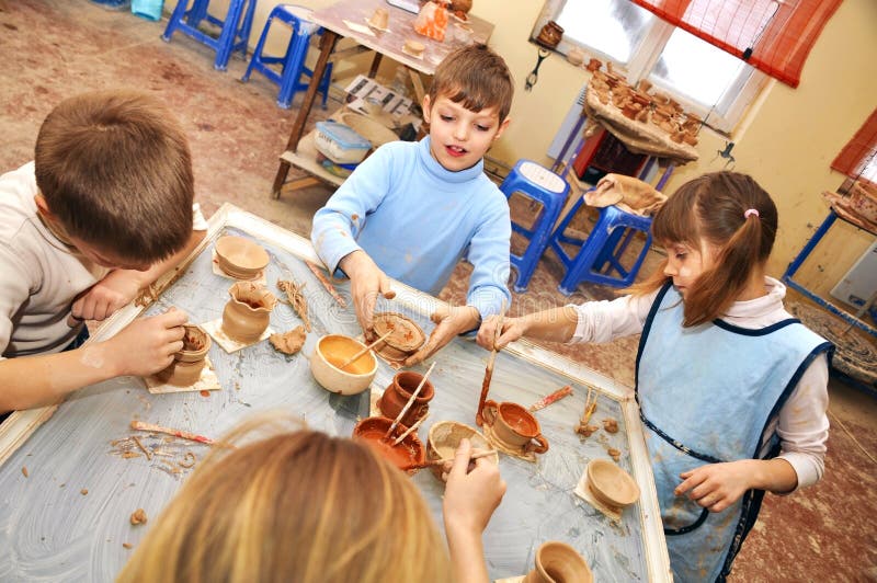 Group of children shaping clay in pottery studio stock images