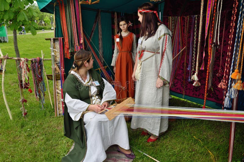 Handcraft fair. MINSK, BELARUS - MAY 23, 2015: Outdoor handcraft fair. Master in national costume making a belt stock photography