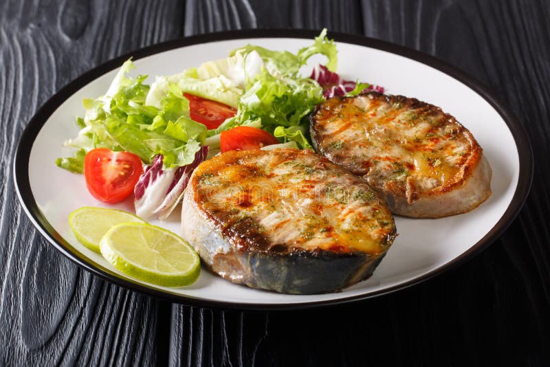 Healthy food fried sturgeon steaks served with fresh vegetable salad close-up on a plate. horizontal. Healthy food fried sturgeon steaks served with fresh royalty free stock photo