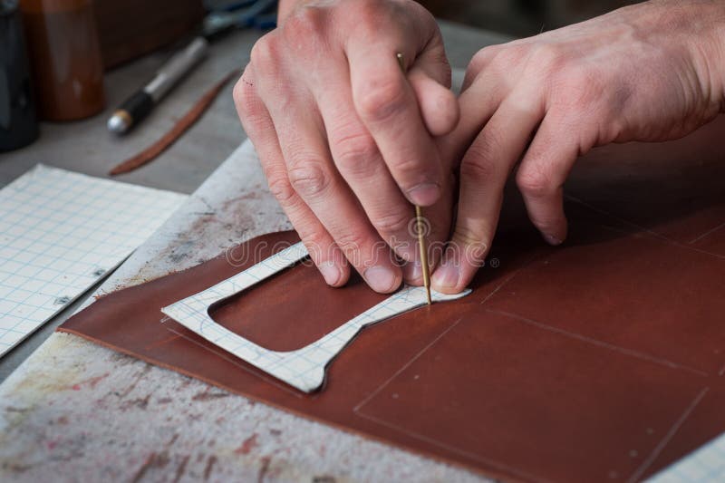 Male hands of master cutting with a knife pattern from genuine leather. Hand-made leather goods manufacturing. Small business concept royalty free stock photo