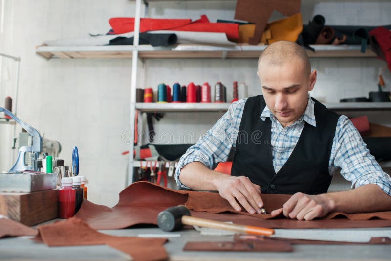 Master a man in an apron cut out leather goods. Small business stock image