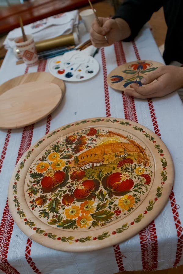 Petrykivka painting style wooden plate, Ukrainian folk art, man`s hands handpainting on a plate, ethnographic master class. Vinnytsia, Ukraine - 19.03.2018 stock photo