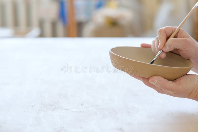 Pottery handcraft hobby paint handmade clay plate. Pottery handcraft hobby. hands painting a handmade clay plate royalty free stock image