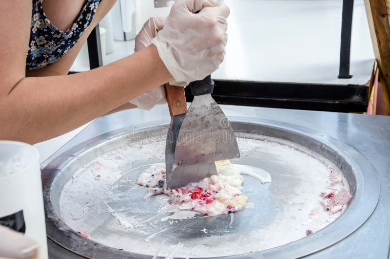 The process of making ice cream on a street ice cream maker. Instant ice cream preparation with a spatula. Cook is preparing ice c stock photo