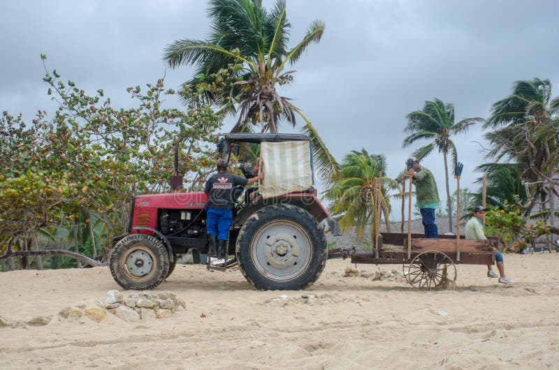 Red Tractor on resort beach clearing weed. Jibacoa Cuba - 25 January 2018: Red Tractor on resort beach clearing weed stock image