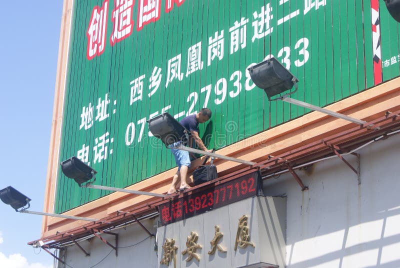 Shenzhen, China: installation of advertising signs. Shenzhen Baoan Xixiang, a worker is installed advertising signs stock images