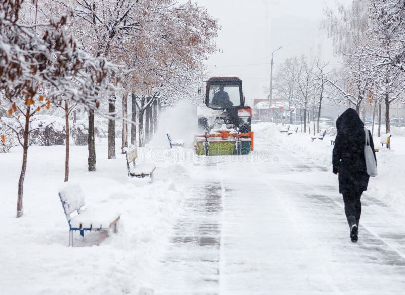 Snow clearing. Tractor clears road, way after heavy snowfall. Tractor cleaning the road from the snow. Excavator cleans the street. S of large amounts of snow in royalty free stock images