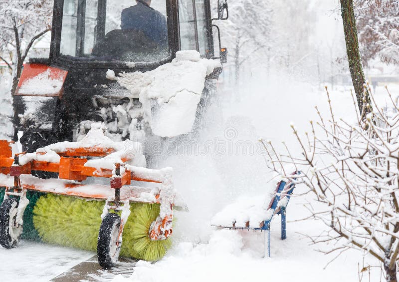 Snow clearing. Tractor clears road, way after heavy snowfall. Tractor cleaning the road from the snow. Excavator cleans the street. S of large amounts of snow in stock photography