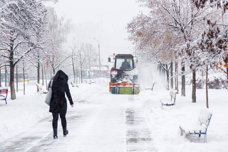 Snow clearing. Tractor clears road, way after heavy snowfall. Tractor cleaning the road from the snow. Excavator cleans the street. S of large amounts of snow in royalty free stock photo