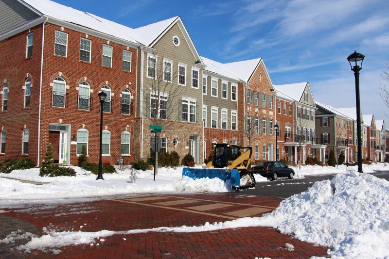 Snow removal around modern townhouses. Clearing snow after a winter storm in the residential area royalty free stock photography