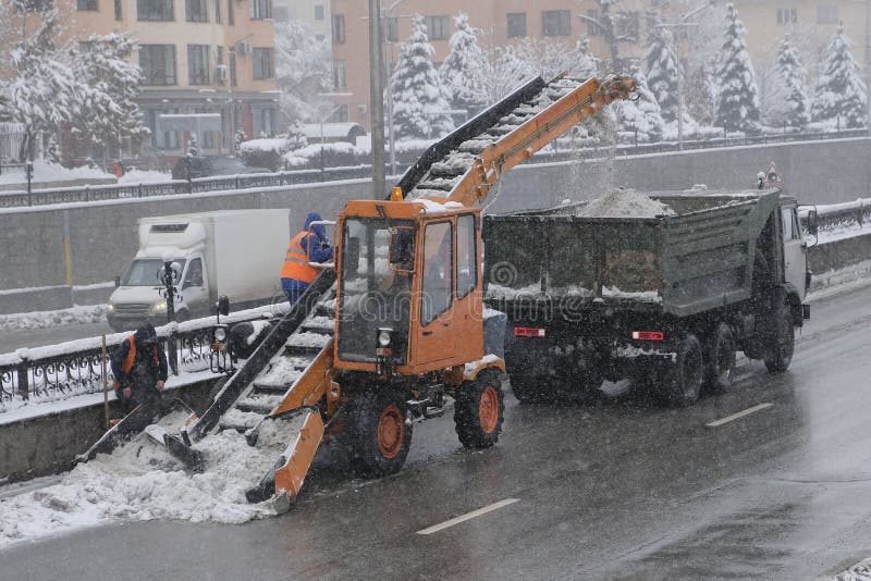 Tractor cleaning the road from the snow. Excavator cleans the streets of large amounts of snow in city stock image
