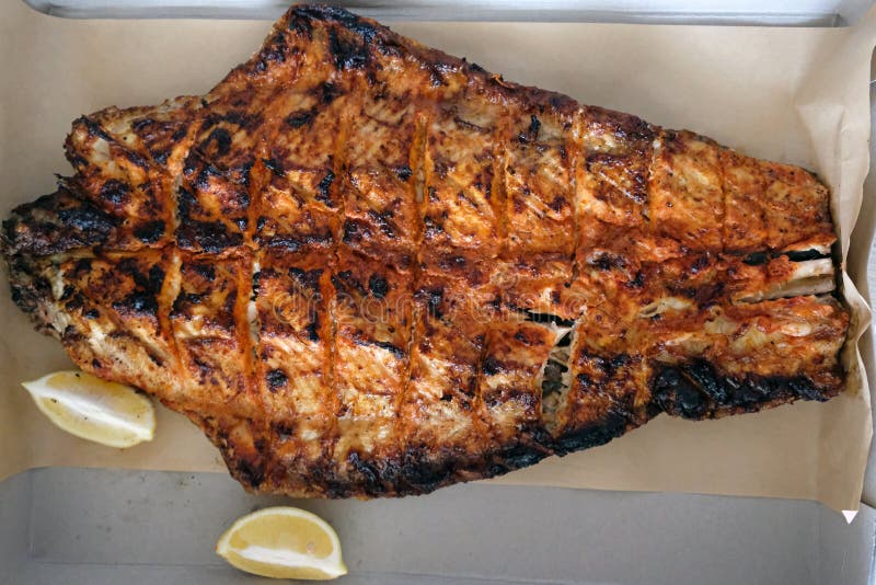 Grilled sturgeon fish. Sturgeon filet top view. grilled sturgeon fish. Lemon slices and fried fish on a sheet of parchment stock photos