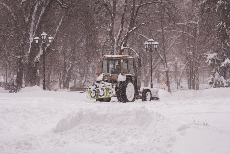 The tractor cleans the snow in the park stock images