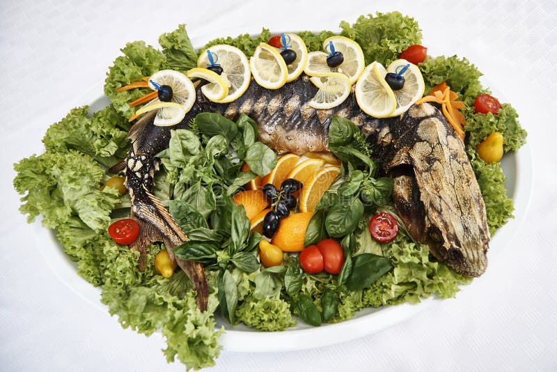 Whole baked sturgeon. With fresh lettuce leaves, vegetables and fruits stock photos