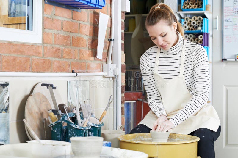 Woman Working At Pottery Wheel In Studio stock image