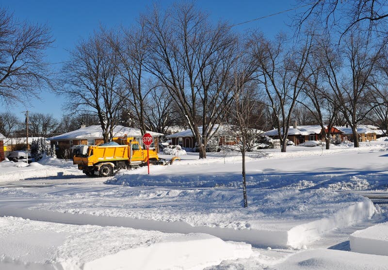 Yellow snow plow truck clearing snow in residential area. Snow plow truck clearing fresh snow after blizzard. Mount Prospect IL, NW Chicago suburb royalty free stock photo