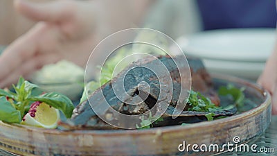 Female Caucasian hands showing fried baked sturgeon fish at camera. Close-up of delicious dish on plate in luxurious. Restaurant. Food industry, culinary stock footage